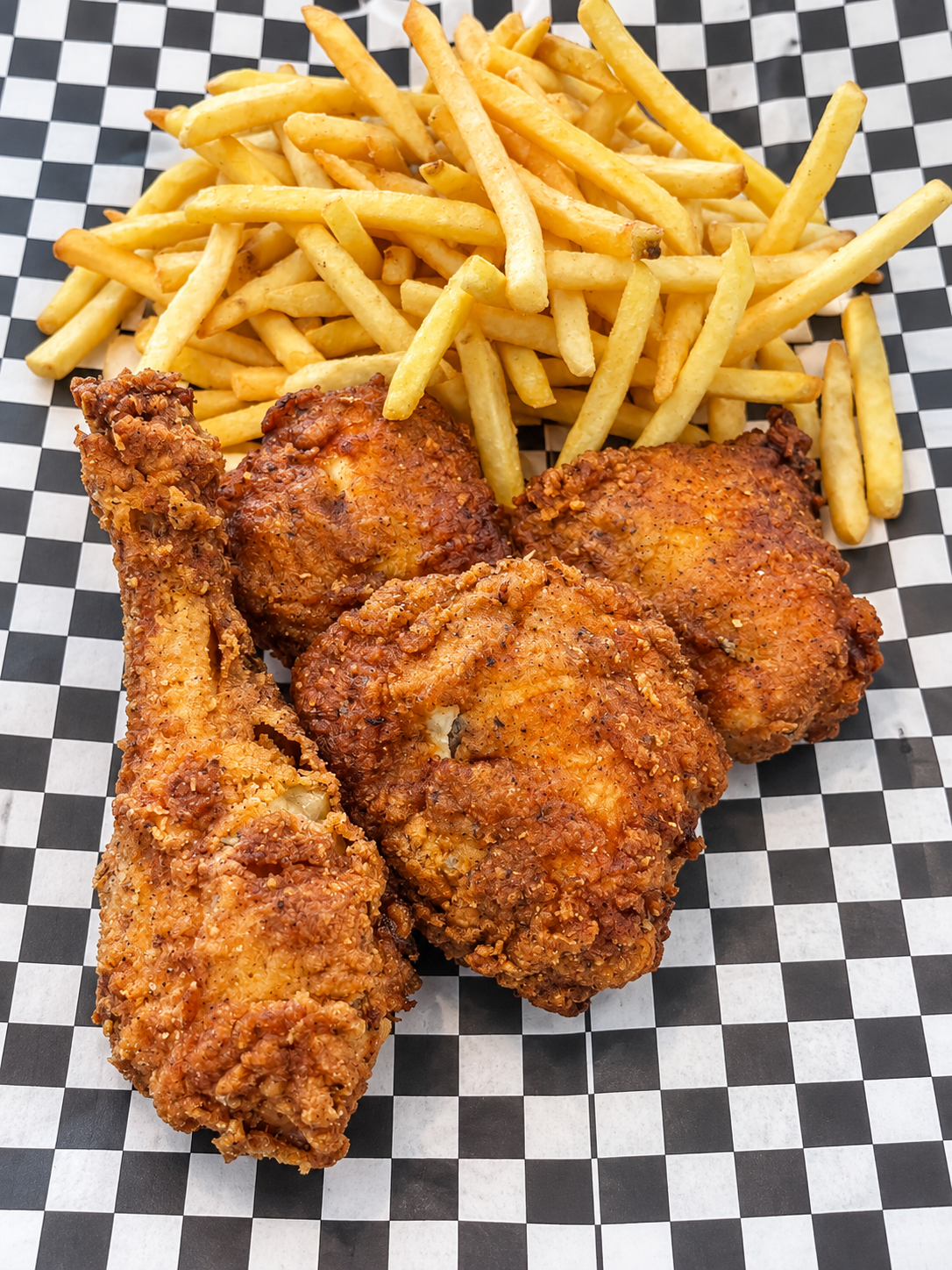 Golden fried chicken and fries on checked paper